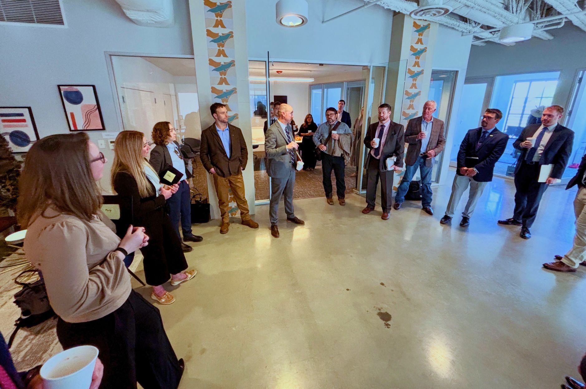 A group of men and women stand in a semi-circle in office attire.